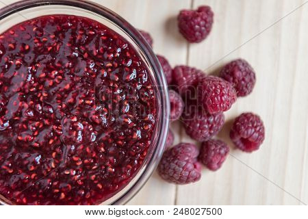 Homemade Raspberry Jam In A Glass Bowl With Fresh Ripe Organic Raspberries On A Wooden Table