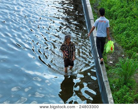PHATHUMTRANI, THAILAND - 21 oktober: oudere vrouw gaat om eten en drinken, maak een wandeling door water dur