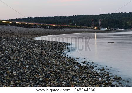 Cars Driving Over Purdy Spit In Washington State At Dusk