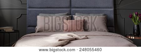 Blanket And Dirty Pink Sheets On Double Bed Standing In Dark Bedroom Interior With Two Bedside Table