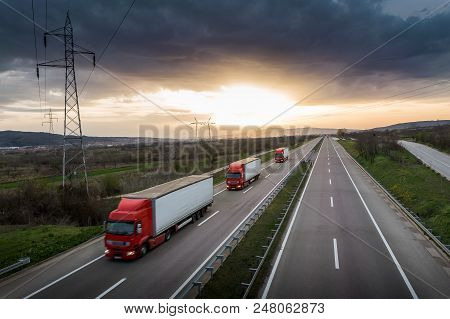 Caravan Or Convoy Of Red Trucks In Line On A Country Highway