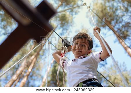 No Acrophobia. Cute Preteen Boy Looking Down And Smiling While Moving Along Trails At An Adventure P