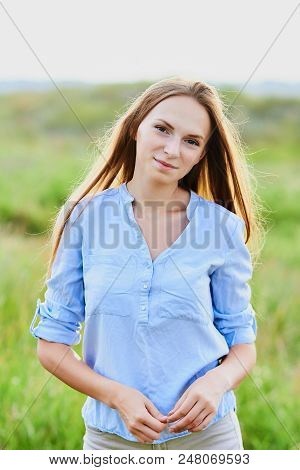 Happy Smiling Young Girl In Blue Shirt And Shorts In The Field