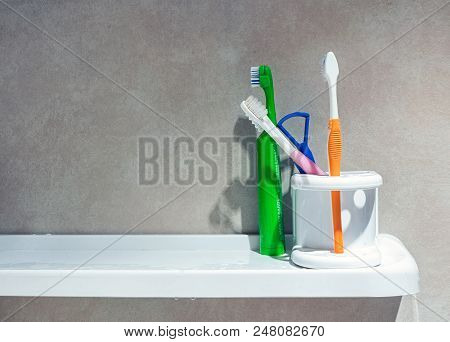 Bangkok, Thailand - June 21, 2018: Various Toothbrushes And A Tongue Scrapper In The Bathroom Shelf