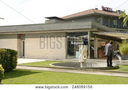 Banyoles, Spain - July 26, 2017: Man Watering The Grass Outdoors A Restaurant Next To The Lake In  B