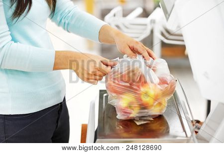 shopping, sale, consumerism and people concept - woman weighing apples on scale at grocery store