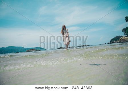 Handsome Girl On The Beach Background. Portrait Of A Woman In White Clothes On The Sea