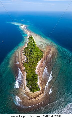 Aerial view of the island of Thanburudhoo with clear water, lush greeery and waves breaking over coral reef. Island is a home for surf spots named Sultans and Honkeyâs. Maldive