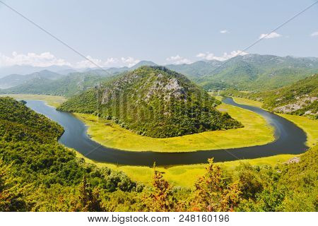 Aerial view of Rijeka Crnojevica flowing through mountains. Location National park Skadar Lake, Montenegro, Balkans, Europe. Scenic image of popular travel destination. Discover the beauty of earth.