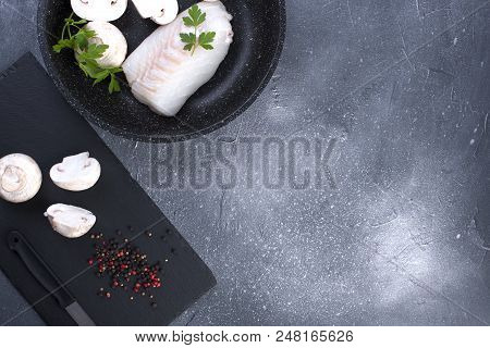 Preparation Of A Seafood Dinner. Fillet Of White Fish On A Black Board With Mushrooms And Spices. Co