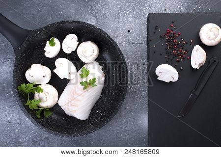 Preparation Of A Seafood Dinner. Fillet Of White Fish In A Black Frying Pan With Mushrooms And Spice