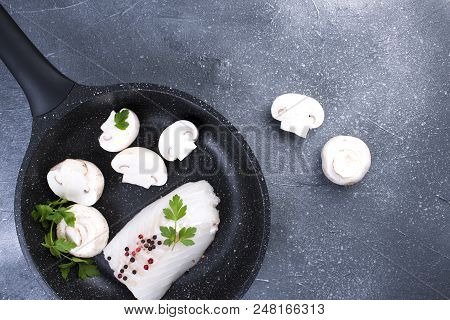 Preparation Of A Seafood Dinner. Fillet Of White Fish In A Black Frying Pan With Mushrooms And Spice