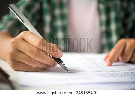 Close Up Of Woman Hands Writing Inon Paper Placed On Wooden In Office