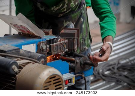 Worker Use Belt Sander To Scrub A Thick Stainless Steel Tube In A Construction Work Site.