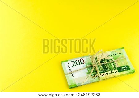A Bundle Of Money. Russian Cash. A Bundle Tied With A Rope. Denominations In 200 Rubles. On A Yellow