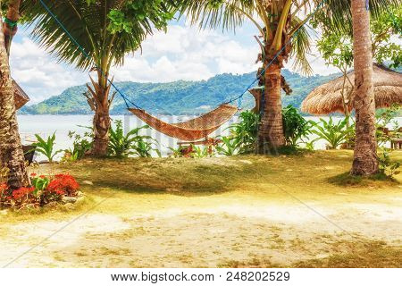 Tropical Beach. A Hammock Between Two Palm Trees On The Beach. Concept Of Rest. Beautiful Beach.