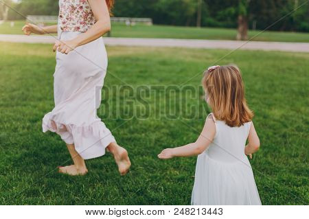 Cropped Little Cute Child Baby Girl Running Catching Up With Joyful Woman In Light Dress On Green Gr