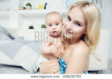 Happy mamm tenderly embracing her small baby at home. Family concept. Healthcare, pediatrics.