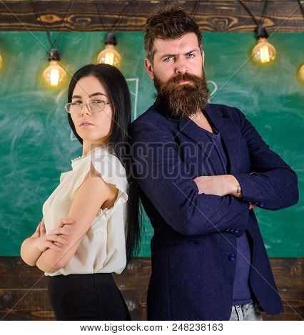 Man With Beard And Teacher In Eyeglasses Stand Back To Back, Chalkboard On Background. Lady And Hips