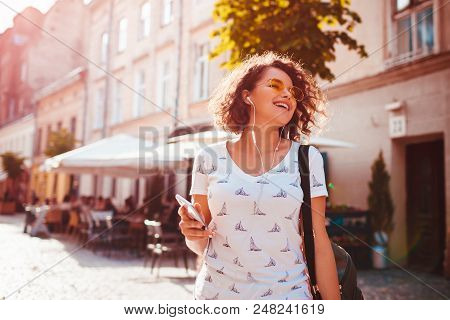Beautiful Young Girl Using Smartphone And Listening To The Music Walking On Street. Happy Woman Danc