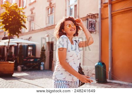 Beautiful Young Girl Using Smartphone And Listening To The Music Walking On Street. Happy Woman Danc