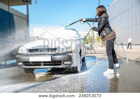 Young Woman Washing Car At Self-service Carwash