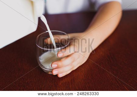 Fresh, Homemade, Store Milk Is Poured Into A Mug. The Boy Is Holding A Mug. The Jet Of Milk. Closeup