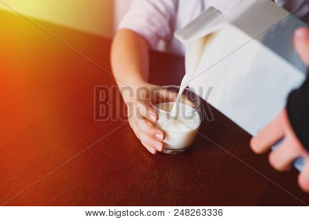 Fresh, Homemade, Store Milk Is Poured Into A Mug. The Boy Is Holding A Mug. The Jet Of Milk. Closeup