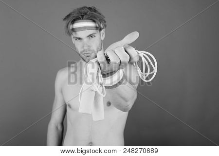 Guy With Bristle Wearing Head And Wristbands. Man With Naked Torso Holds Jump Rope On Pink Backgroun
