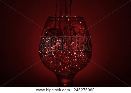 Simple Still-life Photo Of Whisky Glass, Water Jet And Dim Red Light