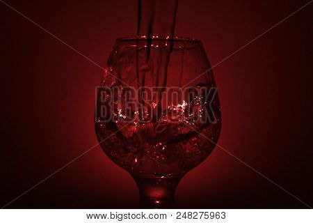 Simple Still-life Photo Of Whisky Glass, Water Jet And Dim Red Light