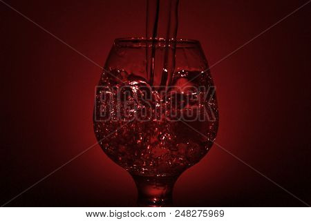 Simple Still-life Photo Of Whisky Glass, Water Jet And Dim Red Light