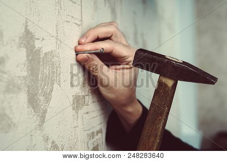 Close-up Of Handyman Hammering A Nail In Board. Concept Of Repair And Renovation. Guy Hammering A Na