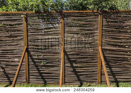 Decorative Wicker Garden Fence On A Clear Sunny Summer Day Background.