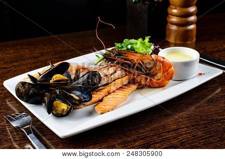 Delicious Seafood Dish. Fish Fillet, Mossels And Prawn Served With Appetizing Sauce In The White Pla