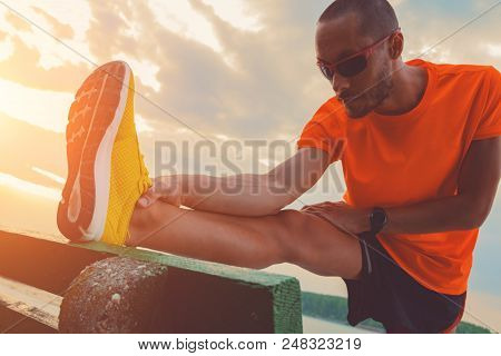 Man Stretching On A Bench Near The River.