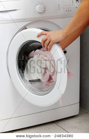 Close-up de uma jovem mulher, colocando um pano em máquina de lavar roupa