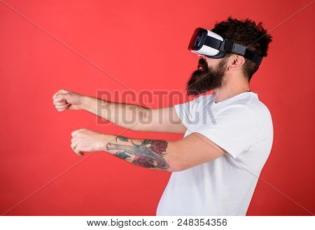 Hipster On Confident Face Driving Bike In Virtual Reality With Modern Digital Gadget. Man With Beard
