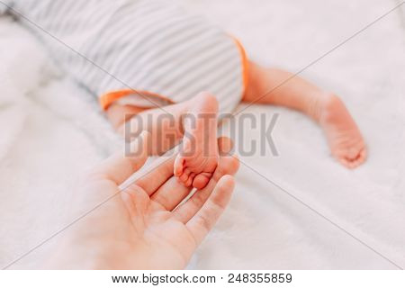Feet Of Newborn Baby In Mother's Hand