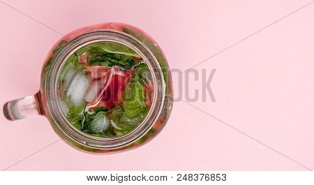 Jar Of Cold Fresh Lemonade With Piece Of Watermelon And Ice On Pink Background.