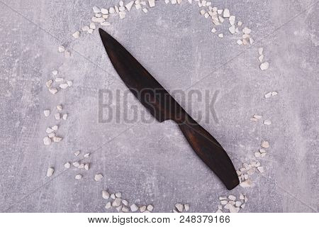 A Wooden Knife Is Situated On The Grey Tabletop, Surrounded With White Decorations.