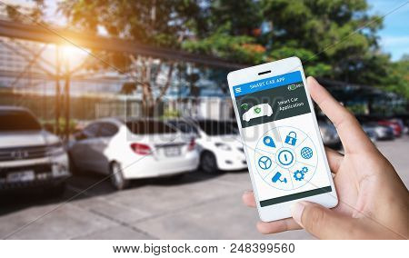 Hand Holding Smart Phone And Application Dashboard With Blur Car Parking Background.