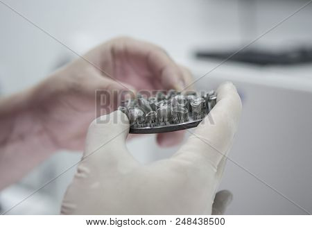 Man Holds In Hands Object Printed On Metal 3d Printer In Laboratory. Dental Crowns Created In Laser 