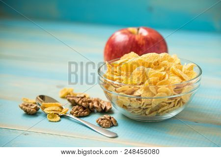 Tasty Cornflakes Witt Walnut And Apple In Glass Bowl On Blue Background. Corn Flakes. Healthy Breakf