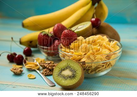 Tasty Cornflakes In Glass Bow With Walnut And Strawberries, Bananas, Kiwi On Blue Background.  Corn 