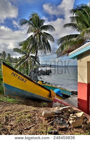 Boat On Barbados Beach With Rocks And Palm Trees Next To Building
