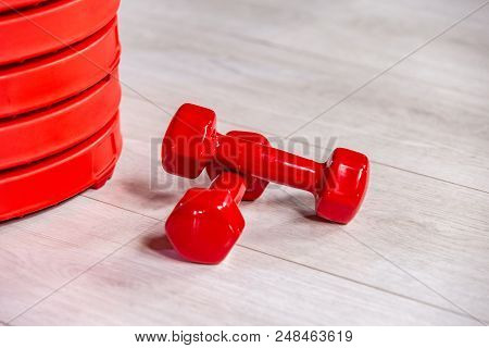 Red Modern Dumbbells And Pancakes For Dumbbells In The Foreground On A Wooden White Floor