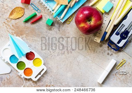 Back To School Concept.  School Supplies, Apple And Origami Plane On A Light Stone Or Slate Backgrou