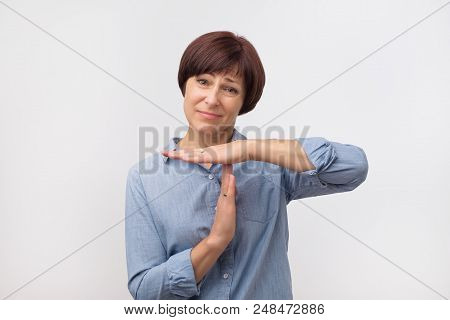 Middle Aged Woman In Blue Shirt Tired And Bored, Making A Timeout Gesture, Needs To Stop Because Of 