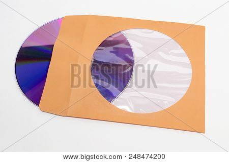 Dvd Compact Disc Sticking Out Of Orange Paper Envelope With Flap And Coated Round Hole To See Conten